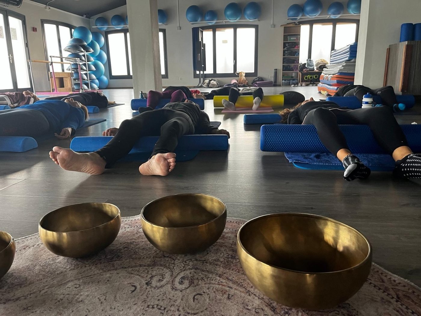 Sessió de sonoteràpia en grup: persones estirades i tres bols tibetans en primer pla