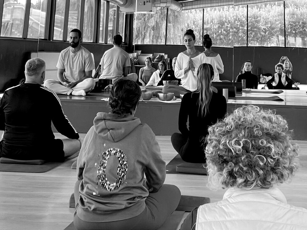 Sergi Colomer i Elisabeth del Río conduint un taller de meditació per a un grup, en blanc i negre